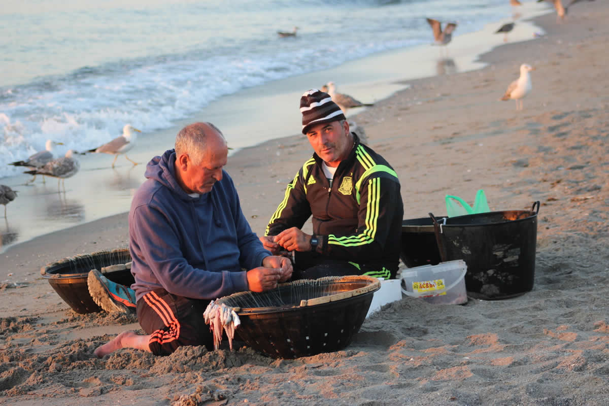 Encarnando el palangre
Durante la mañana, en la playa, una pareja de  marineros encarnan con pulpo el palangre, que será calado en las aguas próximas  para regresar a puerto con &quot;pescado de roca&quot; (doradas, sargos,  besugos, urtas, etc.). Han &quot;echado el rato&quot; desde temprano, con la  aspiración de poder vender las capturas y llevar a casa, a la hora del  almuerzo, el jornal. Entre tanto, se habrán pasado, antes y después de la  faenas, por la taberna, en una rutina que se repite cada día, de cabo a cabo  del año. (Autor: David Florido).